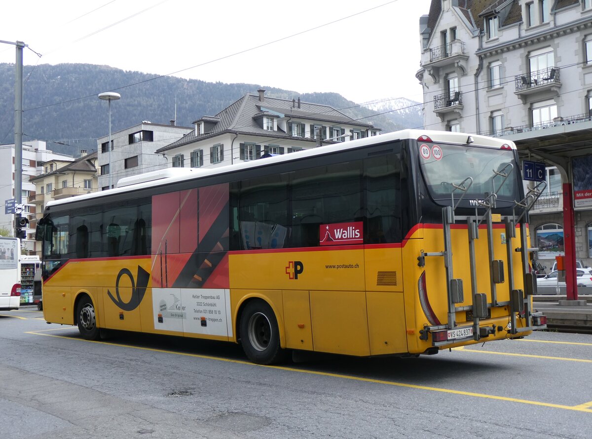 (261'832) - PostAuto Wallis - VS 424'837/PID 10'083 - Iveco am 29. April 2024 beim Bahnhof Brig