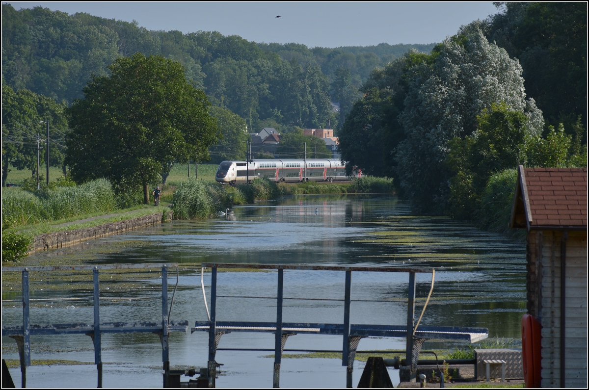 Am Rhein-Rhone-Kanal.

Die TGV-Einheit der neuesten Generation eilt auf der schwach frequentierten Altstrecke Richtung Paris entlang des Rhein-Rhone-Kanals. Der Zug Nr 816 hat eine Luxemburgzulassung, auch wenn er nicht in diese Richtung fährt. Die Triebköpfe haben die Nummern 93 87 0310 231-0 F-SNCF und 232-8. Brunstatt, Juli 2021. 
