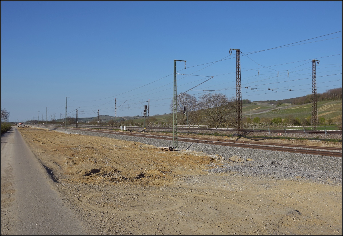 Baufortschritt zwischen Schliengen und Auggen. Die neue Oberleitung auf dem rheinseitigen Gleis ist in diesem Abschnitt bereits fertiggestellt. Die Gleise der künftigen Regionalstrecke liegen beide schon. Eines von zwei Tragwerken der Oberleitung auf der Altstrecke ist im Bild zeugt noch vom ehemaligen Bahnhof Schliengen. April 2021.