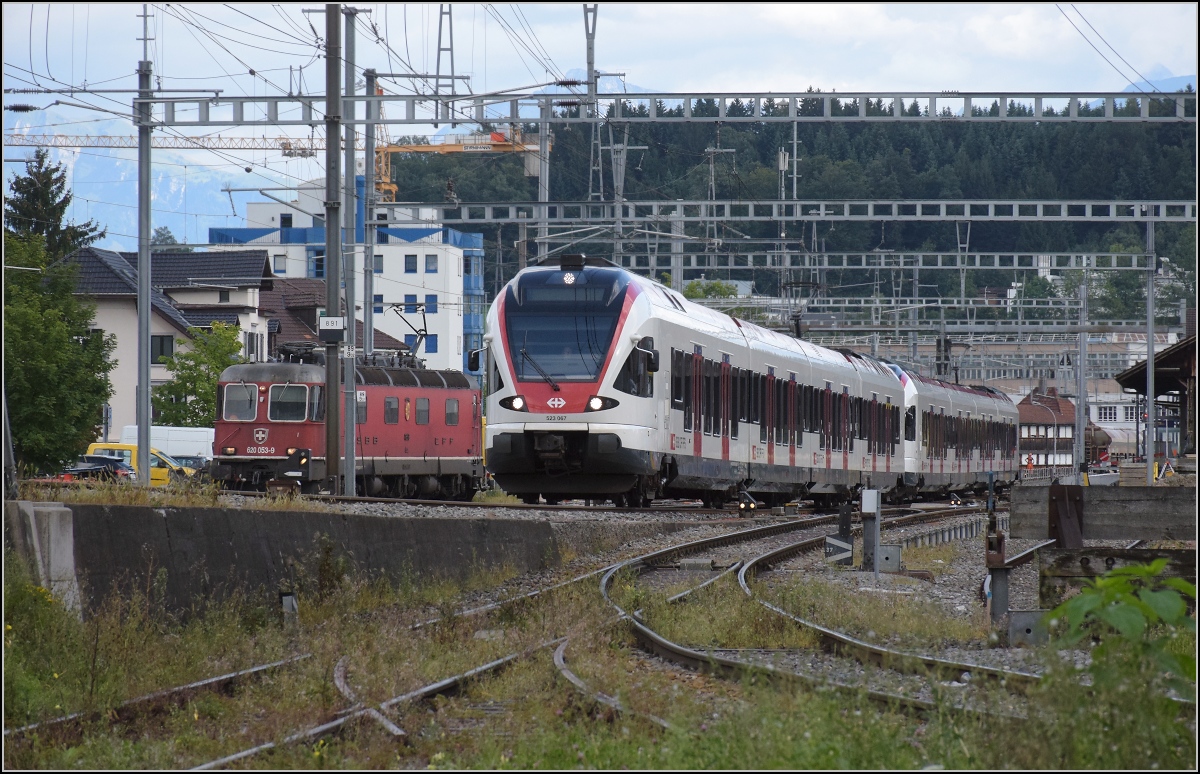 RABe 523 067 und RABe 523 070 nach Sursee in Emmenbrücke. Dahinter Re 6/6 11653 'Gümligen'. August 2021.