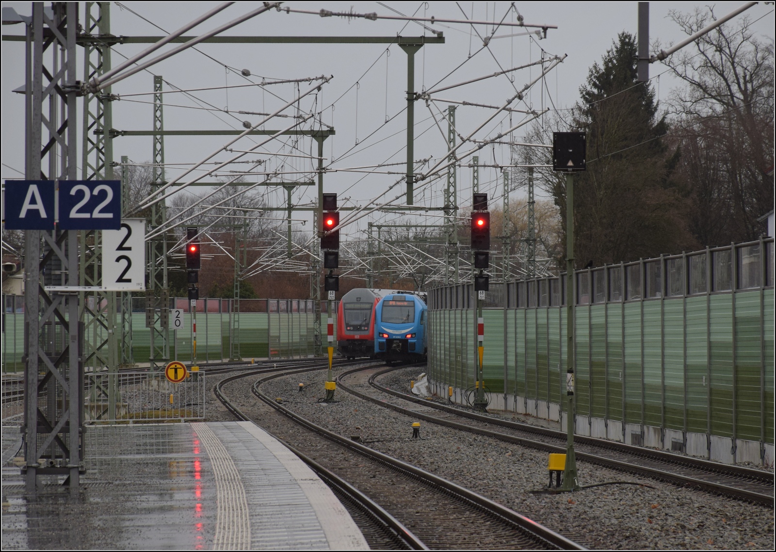 146 203 mit einem Regionalexpress Richtung Stuttgart in Lindau-Reutin hat scheinbar eine Parallelausfahrt mit 1428 028. Tatsächlich muss aber einer der Züge warten, da sich ihre Wege kreuzen. Februar 2023.