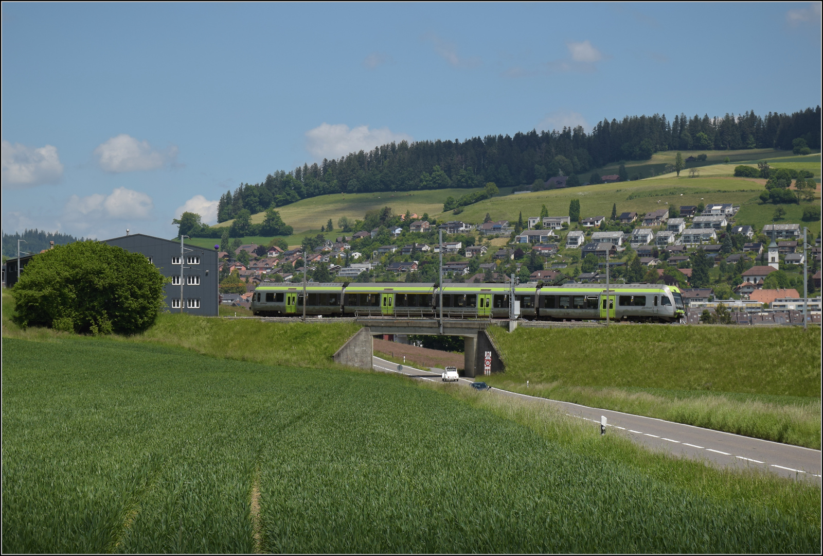 150 Jahre Emmentalbahn. 

Die Rampe von Konolfingen nach Grosshöchstetten (im Hintergrund) war einst ein grösseres Betriebshindernis für die Bahn. Die Burgdorf-Thun-Bahn schlug den Steigungsproblemen ein Schnippchen, indem sie von Anfang an mit Drehstrom fuhr. Im ersten Weltkrieg profitierte die Bahn von ihrer nachhaltigen Energieversorgung und profitierte sogar von der Krise. Das hätte man den Herren von Nordstream und Co. mal vor die Nase halten sollen. Der Strom wird zwar heute  als Wechselstrom mit nur einer Phase übertragen, das Prinzip des Drehstromantriebs beherzigt aber der Lötschberger Kollege RABe 535 121, der hier nach Grosshöchstetten hinauffährt. Konolfingen Dorf, Mai 2025.