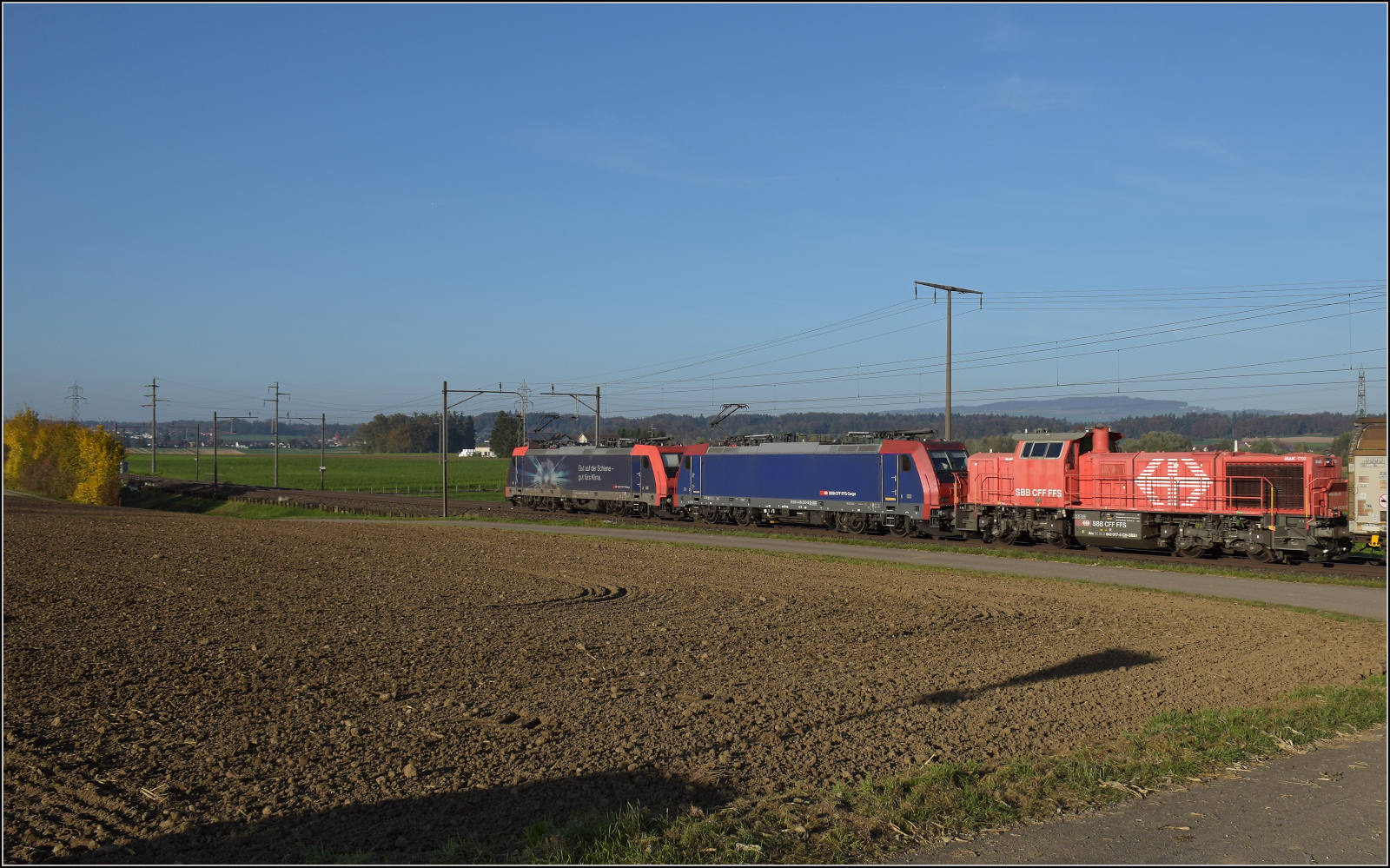 Aargauische Südbahn.

Re 484 020 'Gut für's Klima' und Re 484 013 nehmen in ihrem Zug Am 843 017 mit. Boswil, November 2024.