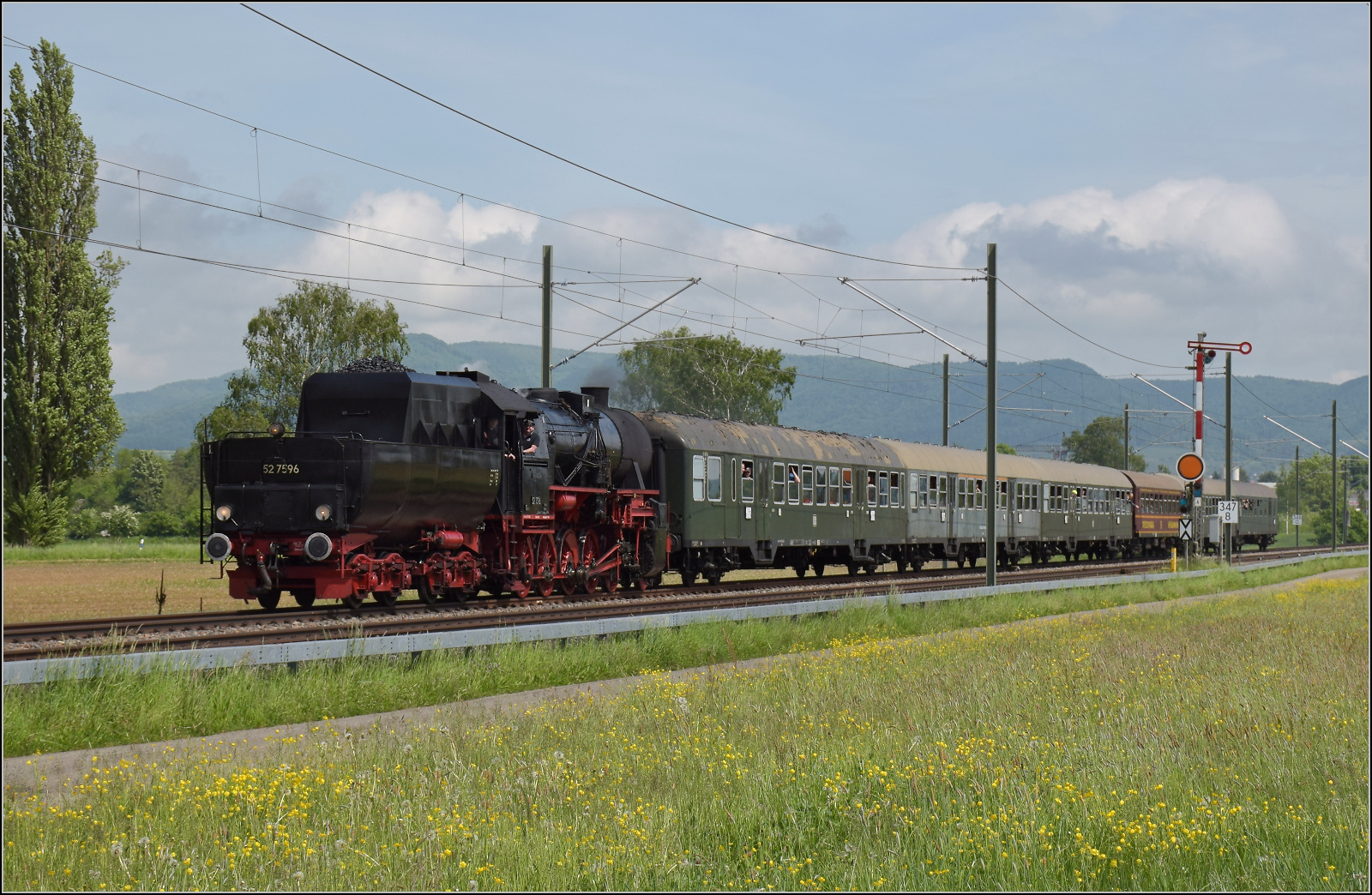 Abschiedfahrten von 52 7596.

Bei Wilchingen-Hallau befindet sich der Zug in der Schweiz. Im Hintergrund das Randengebirge, dessen Reliefenergie von ber 500 Metern auer von hier kaum irgendwo sichtbar ist. Mai 2025.