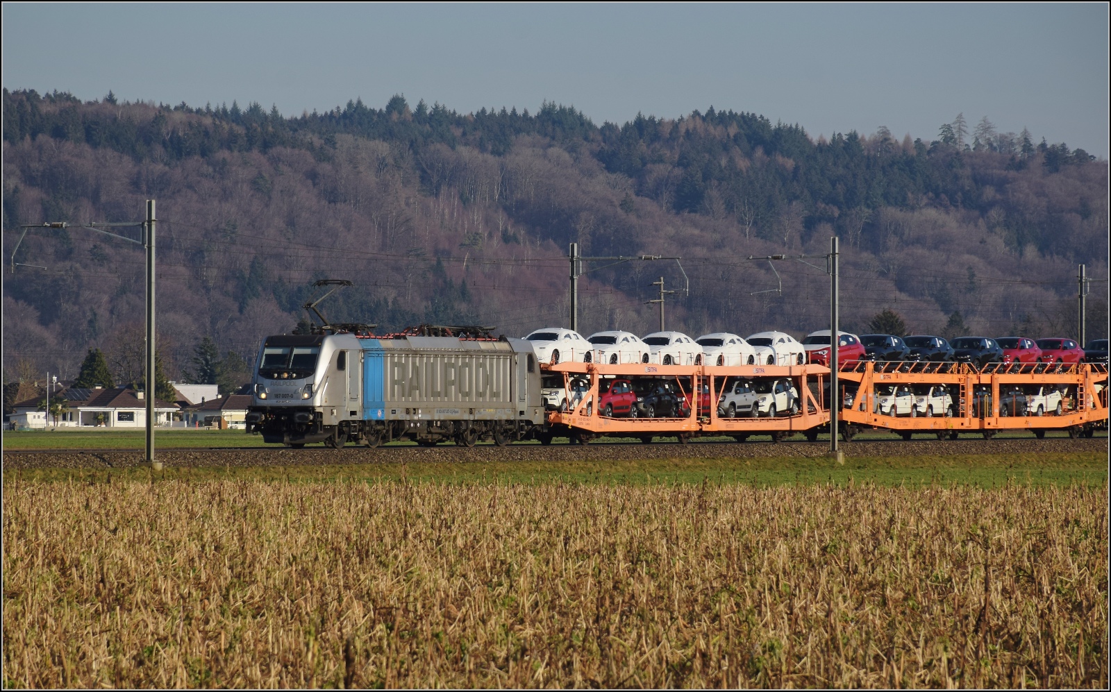 Am fast dauerverschlossenen Bahnbergang.

187 007 der Railpool mit einer Ladung Alfa Romeos in Hendschiken. Februar 2023.