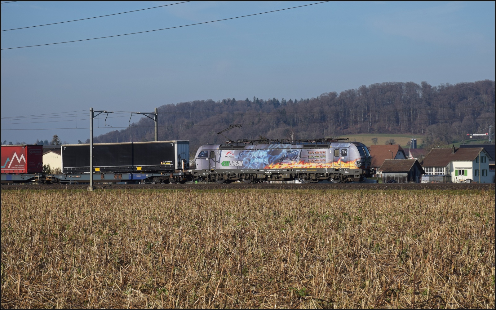 Am fast dauerverschlossenen Bahnübergang.

193 282 der ELL mit der Message 'The future is on tracks' und einer Klimauhr in Hendschiken. Februar 2023.