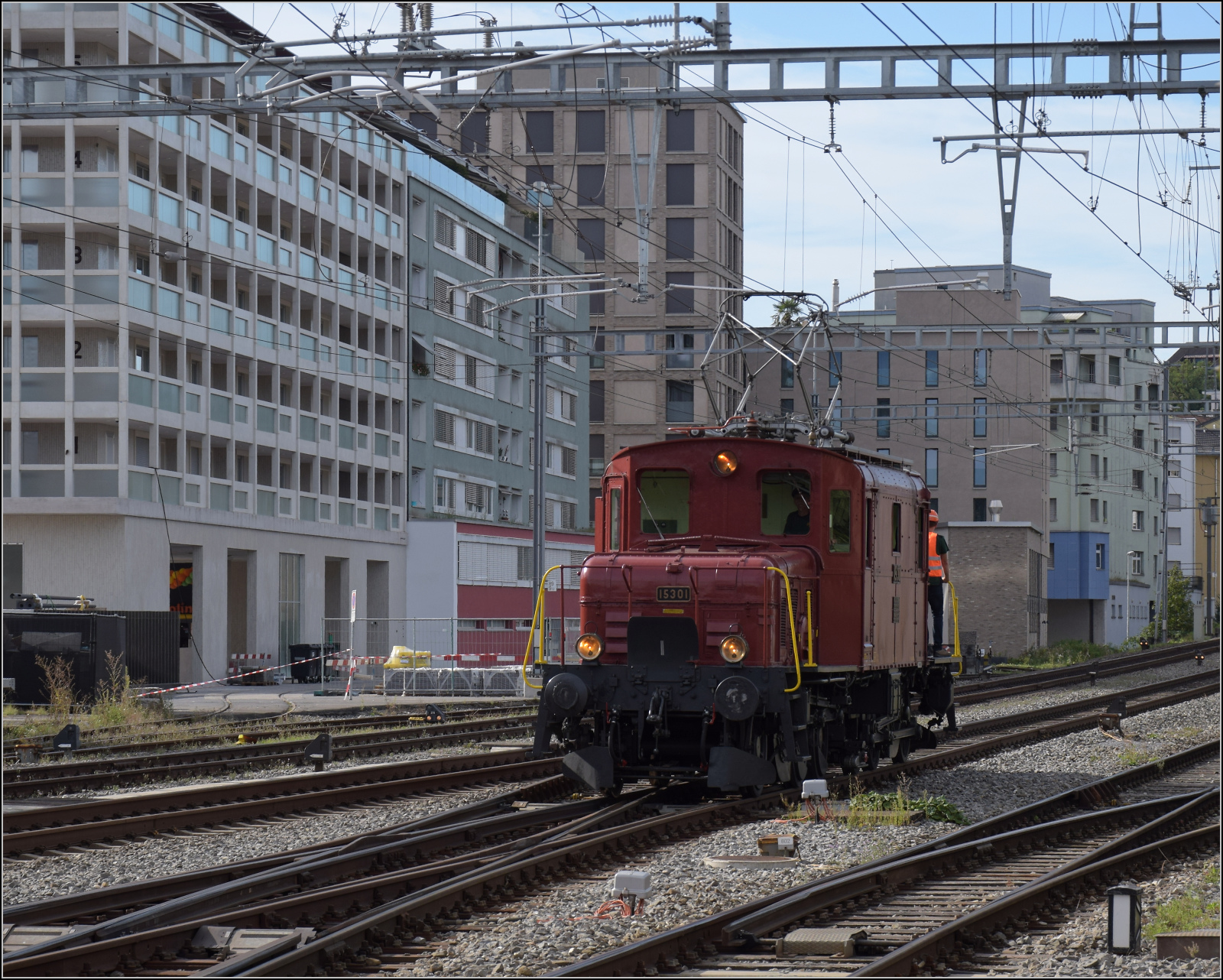 De 6/6 15301 rangiert in Emmenbrcke auf die andere Seite des Zuges. Unter dem blauen Wrfel im Haus fhrt die Werksbahn durch das Haus zum Stahlwerk. September 2024.