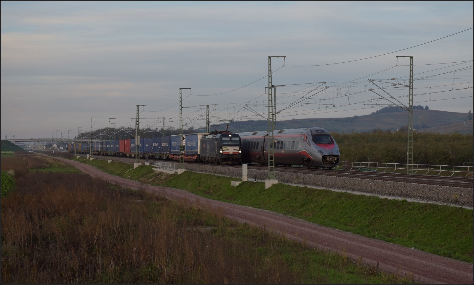 Der unbekannt gebliebene ETR 610 der Tren Italia trifft auf 193 713 der MRCE für die BLS und Crossrail bei Auggen. November 2022.