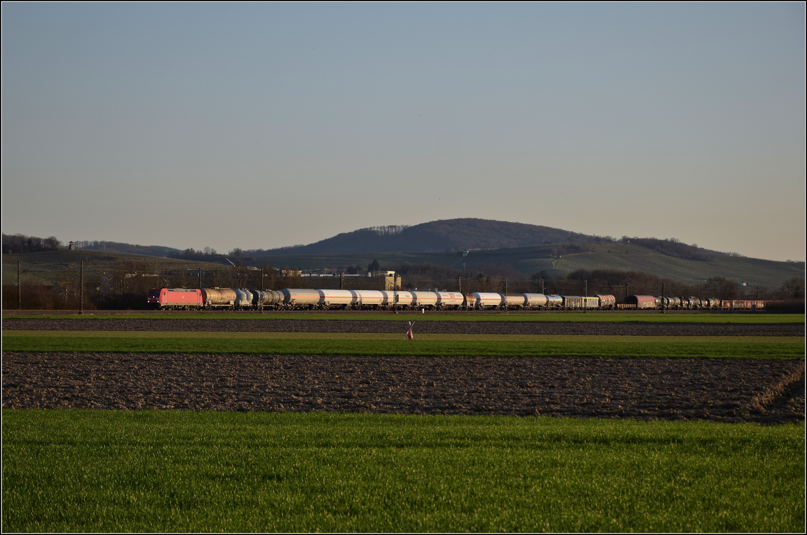 Die Abendstimmung hat längst eingesetzt als 185 270 mit einem Mischer bei Hügelheim nordwärts vorbeizieht. Februar 2026.