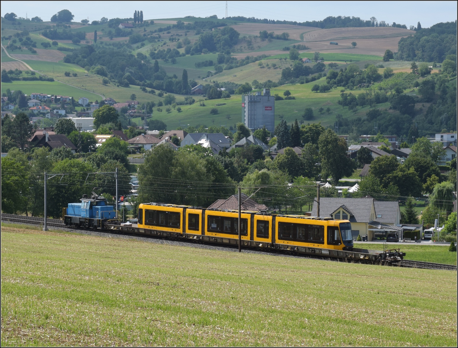 Die Stadler-Werkslok Eem 936 131 liefert eine neue TINA-Strassenbahn nach Darmstadt aus. Auf dem Weg in Frick, Juli 2023. TINA steht für: Total Integrierter Niederflur Antrieb. Damit wird in Darmstadt die neueste Technologie von Stadler erstmals in Betrieb genommen. 