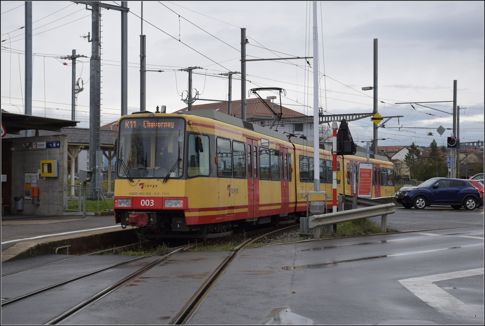 Die Strassenbahn  Be 4/8 003  alias 94 800 450 003-9 D-TVYS wartet in Chavornay auf die Fahrgäste der S-Bahnen. Dezember 2025.