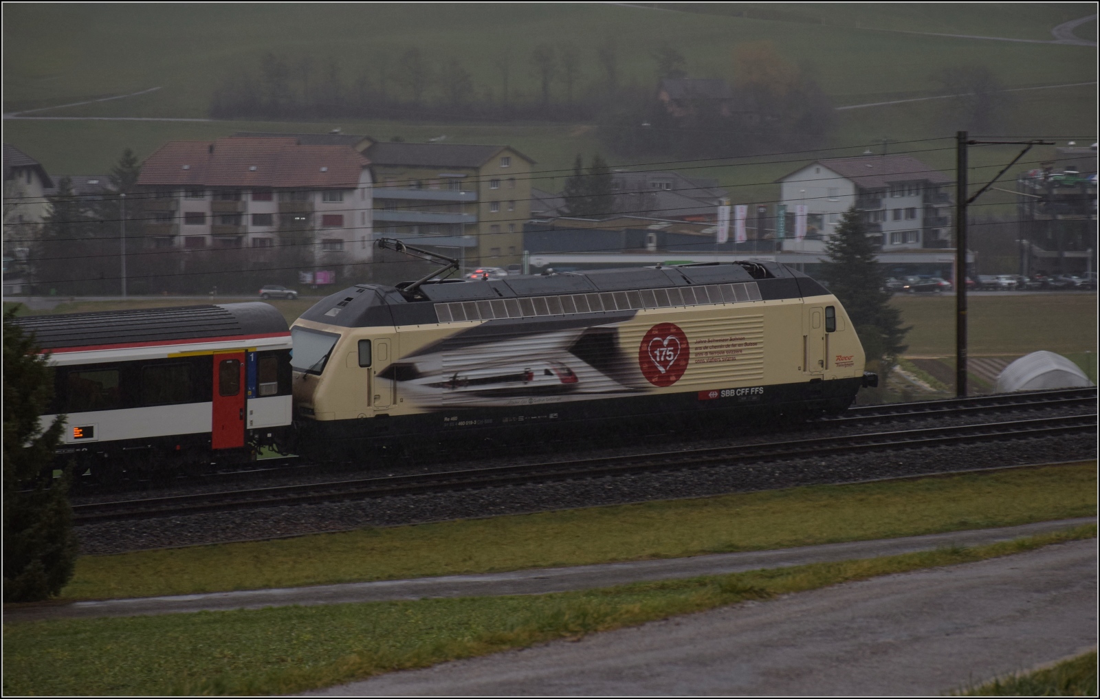 Dunkle Regenschlacht an Silvester.

Re 460 019 mit der Bahnjubiläumswerbung bei Frick. Dezember 2023.