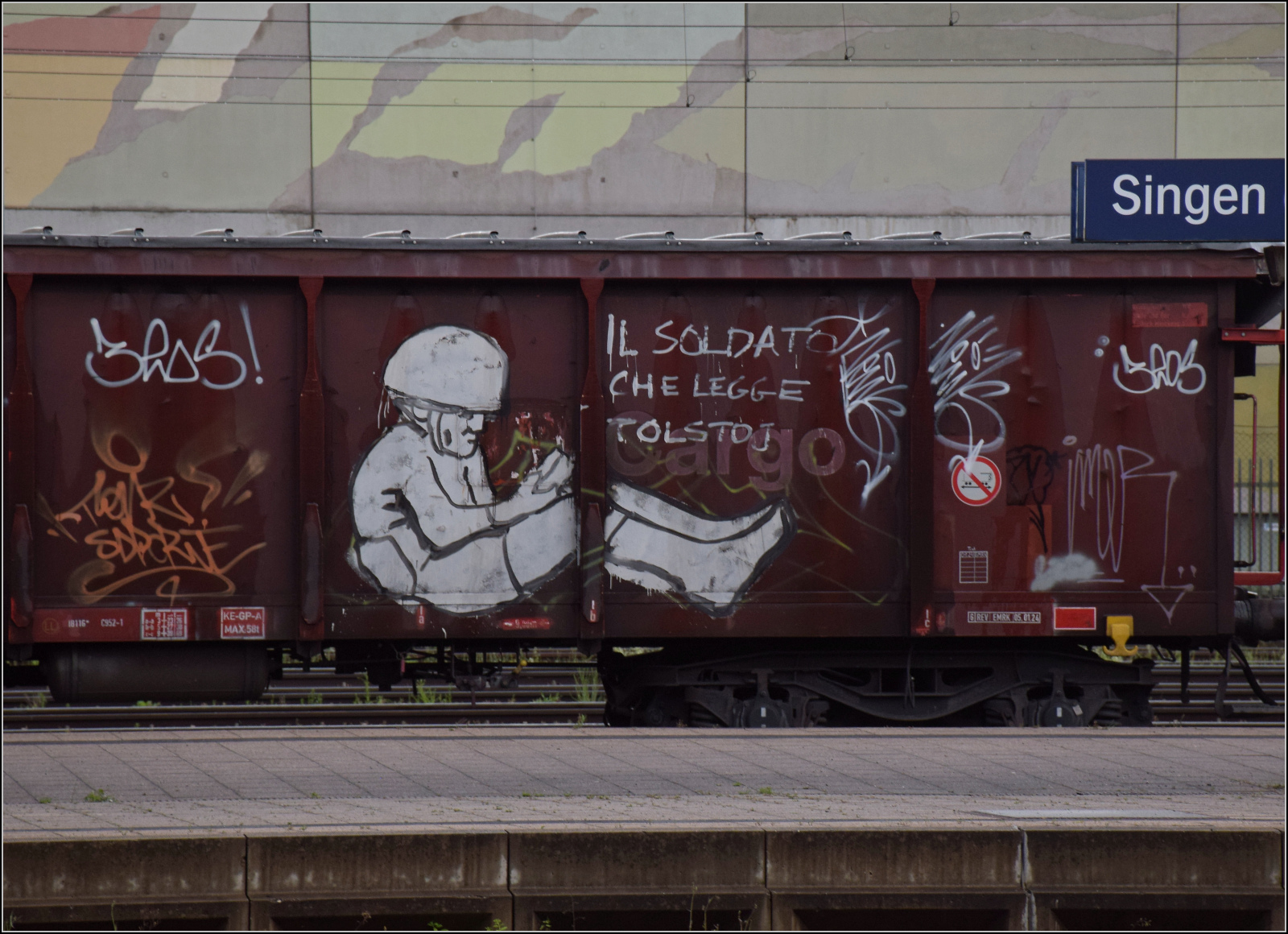 Ein offener Güterwagen in Singen mit dem bemerkenswerten Graffito 'Il Soldato che legge Tolstoj'. Juni 2025.