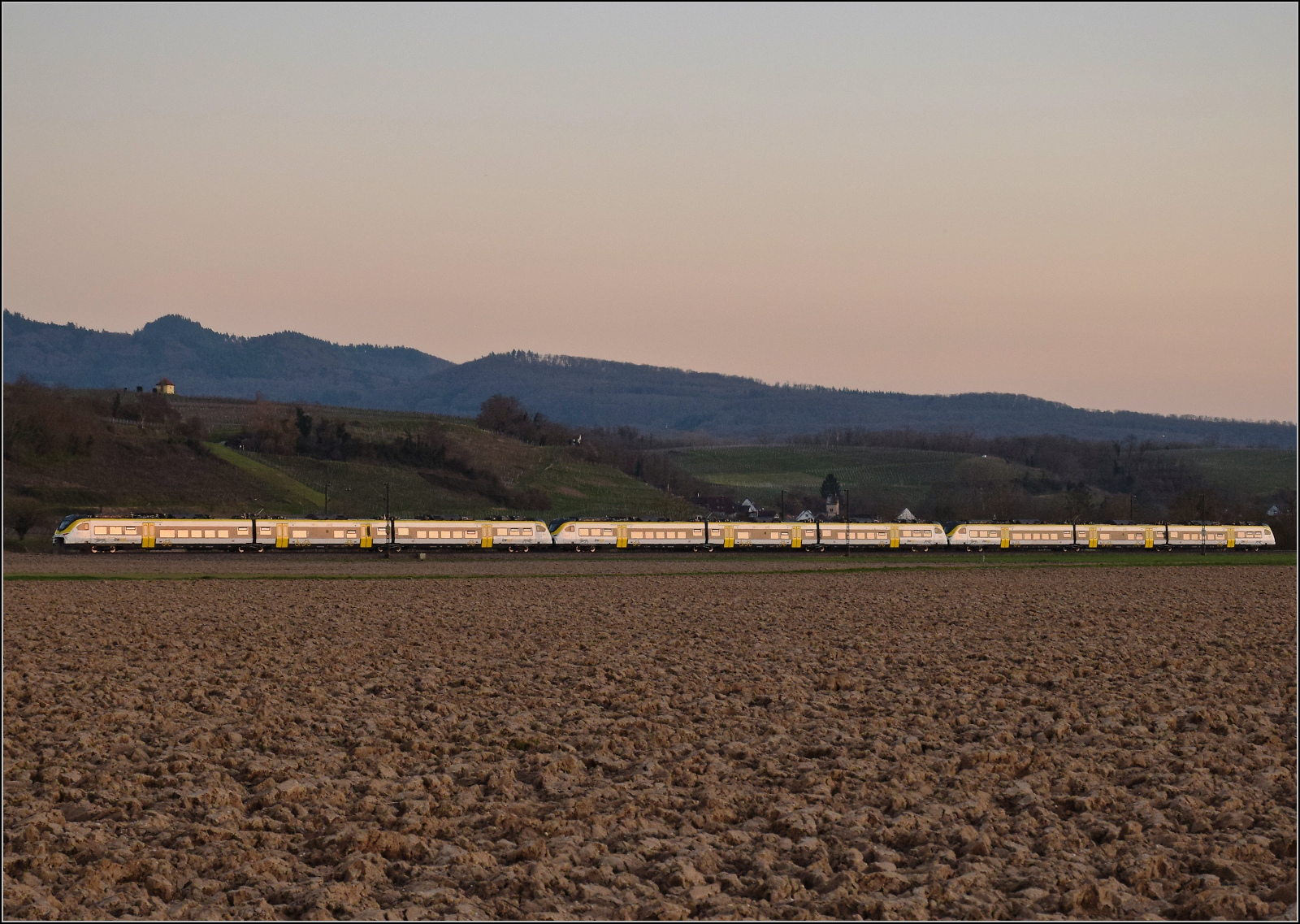 Ein unbekannt gebliebenes Dreierpack 463 im Bwegt-Design fährt bei Buggingen im letzten Abendlicht südwärts. Februar 2026.