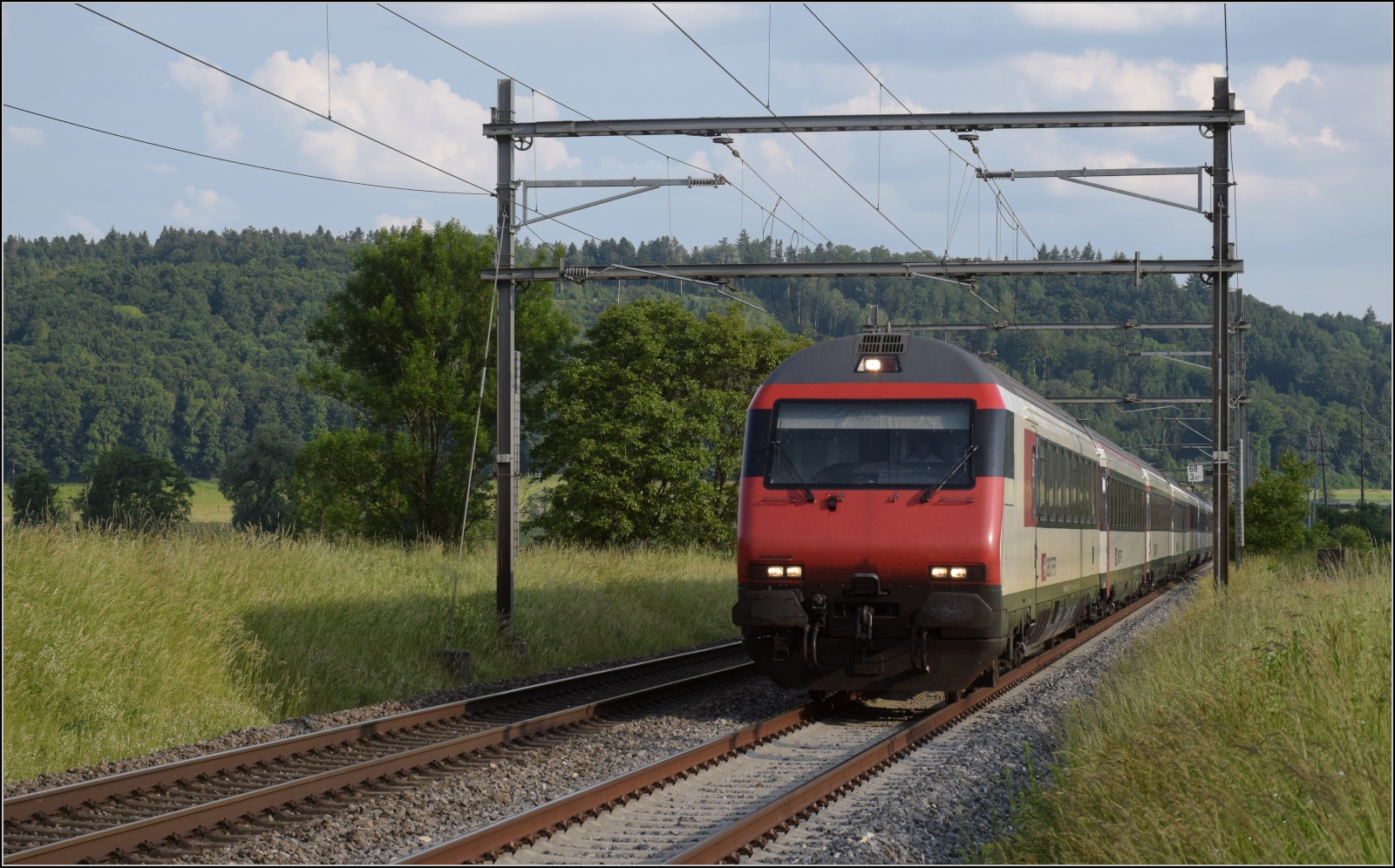 EW IV Steuerwagen voraus schiebt eine Re 460 bei Bettenhausen einen Schnellzug. Juni 2023.