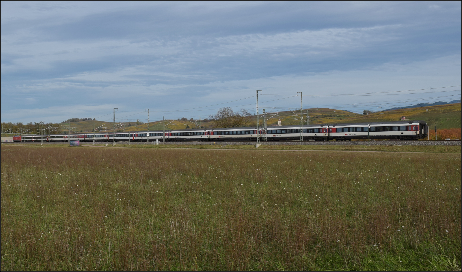 Herbst in Auggen.

101 134 mit dem EC 6 auf dem Weg nach Dortmund. Im Bild ist der ganze Zug mit den Schweizer Eurocitywagen von hinten betrachtet. Ein echter Zugschluss ist bei Personenzügen heute fast nicht mehr zu beobachten. Oktober 2025.