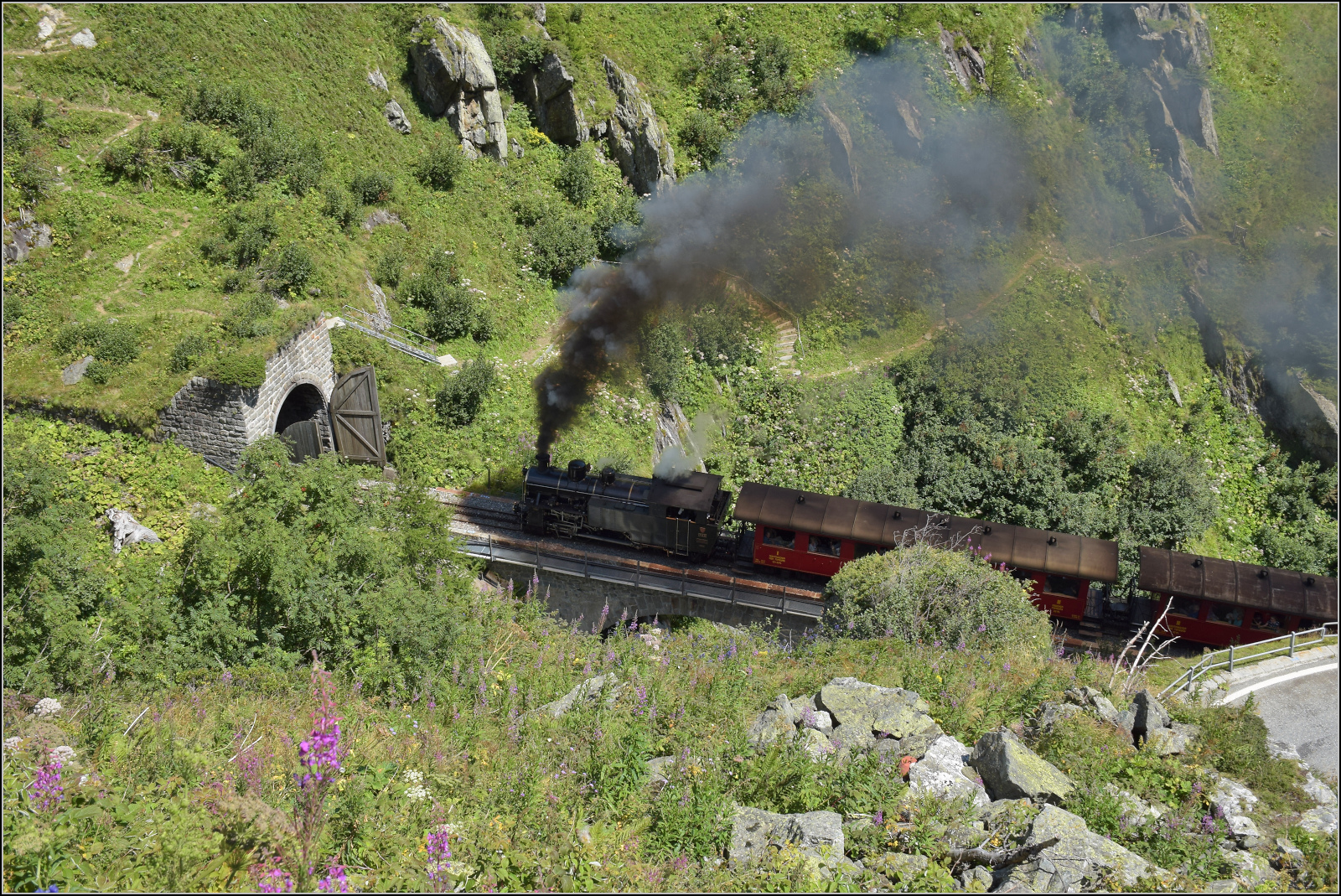 HG 4/4 704 erklimmt mit ihrem Zug die Rampe von Oberwald nach Gletsch. Hier geht es in den Kreiskehrtunnel rein. August 2025.
