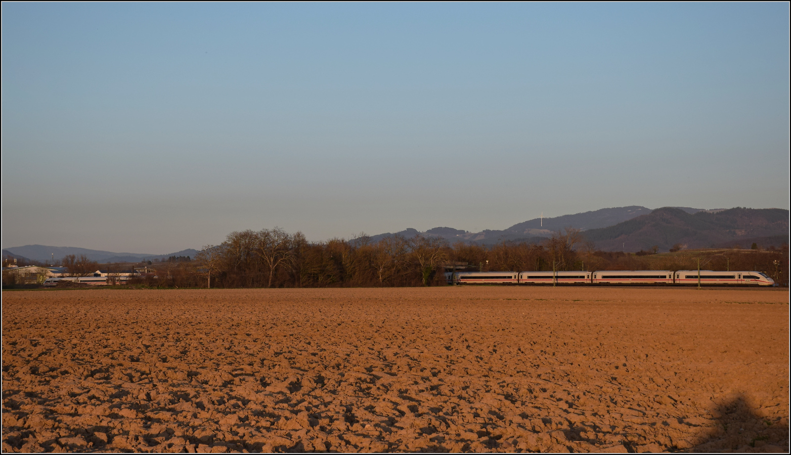 ICE 4 '412 072' fährt in noch starker Abendsonne bei Buggingen nordwärts. Februar 2026.