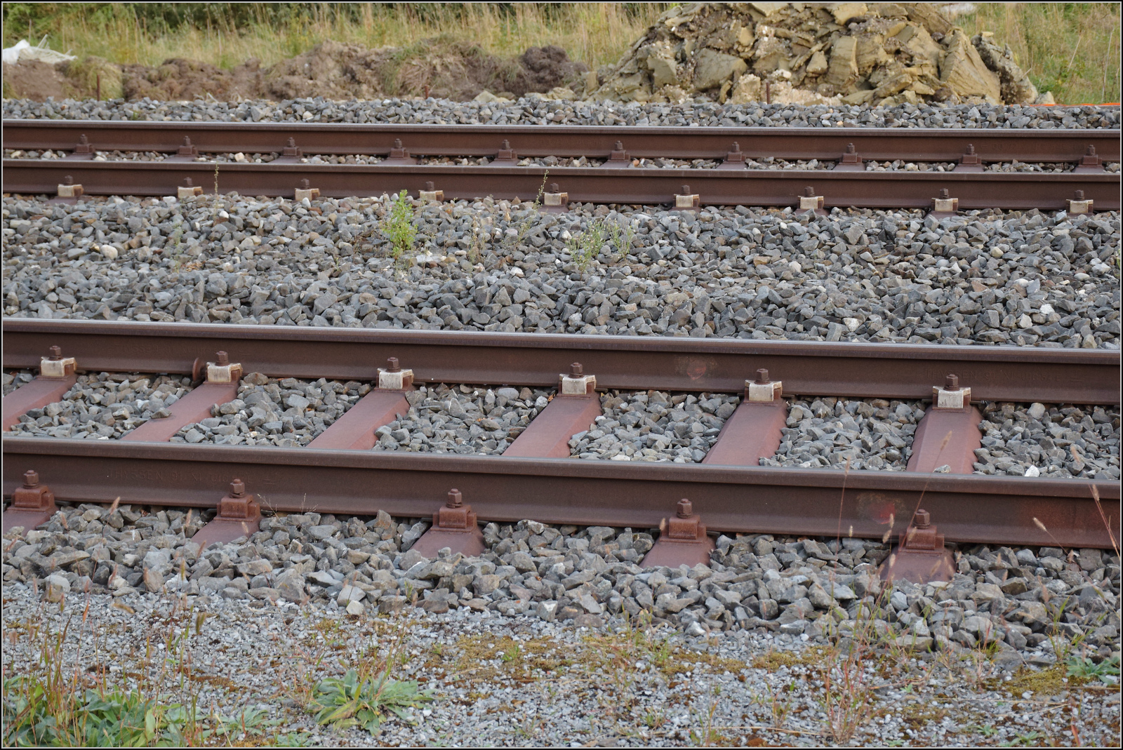 Jurabahn vor der Generalsanierung im Abschnitt Sanceboz-Sombeval – Moutier.

Diese Schiene an Gleis 2 in Court tr�gt das Walzzeichen THYSSEN 91 XI UIC 54 E und ist auf einem Sammelsurium �lterer Schwellen montiert. Somit sind das Durchgangsgleis 3 durchgehend und das Gleis 2 f�r den Regelverkehr ausser den Weichen zum Gleis 1 mit dem heutigen Regelprofil versehen. September 2026. 