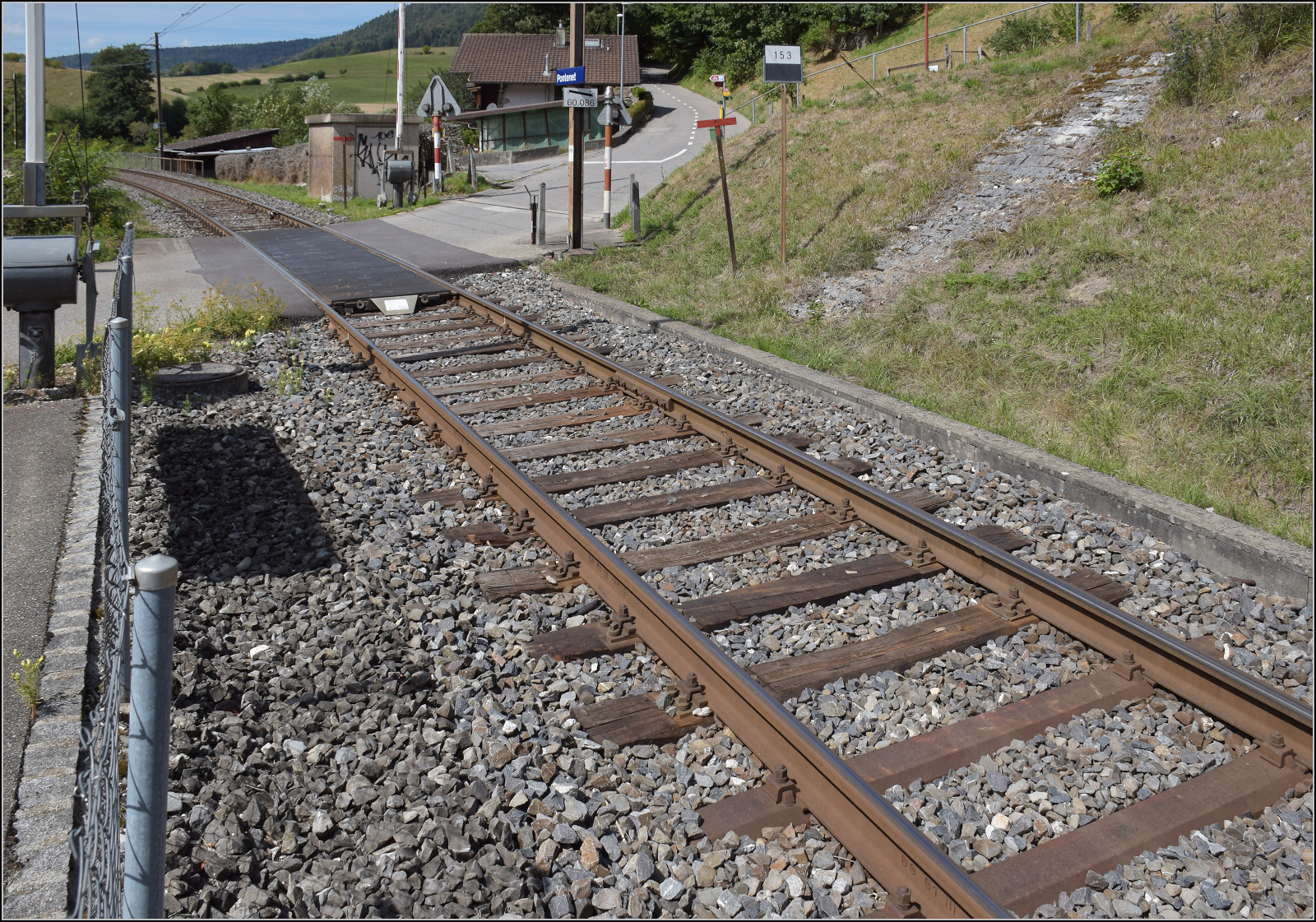 Jurabahn vor der Generalsanierung im Abschnitt Sanceboz-Sombeval – Moutier.

Pontenet ist ein minimalistisch gestalteter Haltpunkt, die eher unver�ndert bleiben d�rfte. Der Weg zur Siedlung f�hrt diese ebenso minimalistische Strasse hinauf. Man beachte die Holzschwellen im Bahn�bergangsbereich. August 2026.