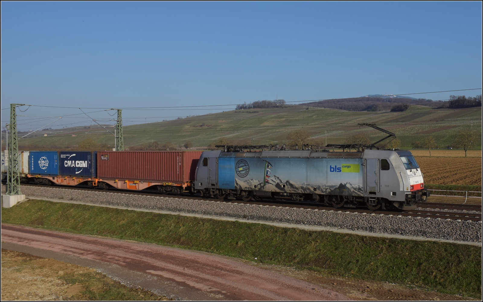 Nachmittag im Markgräfler Land. 

186 103 der Railpool fährt für die BLS bei Auggen. Februar 2023.