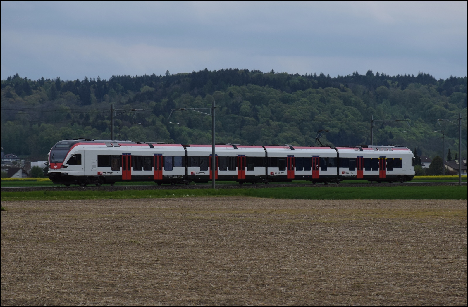 RABe 523 038 bei zwischen Henschiken und Dintikon-Dottikon. Wer nun glaubt, an einem Sonntag könnte man im Nachgang auf dem Gotthardzulauf noch ein paar Güterzüge abpassen, der stellt schnell fest, hier ist Flirtland. April 2023.