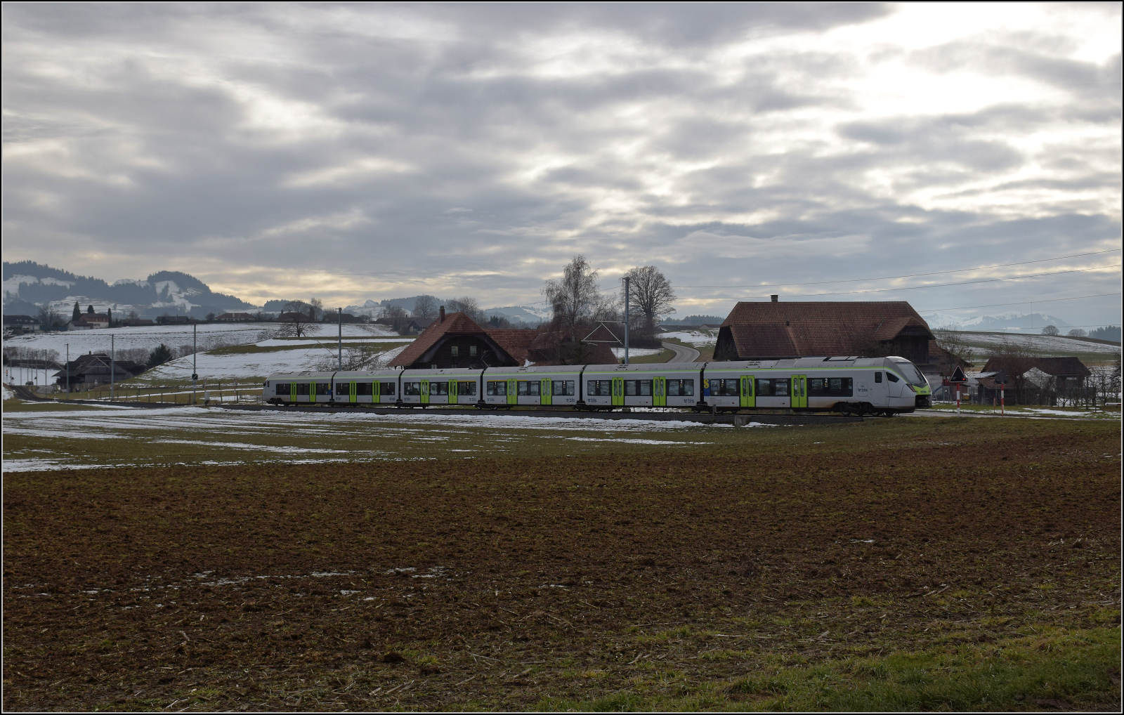 RABe 528 213 ist kein Mika sondern KAMI und bei Häusern auf dem Weg nach Schwarzenburg. Januar 2026.