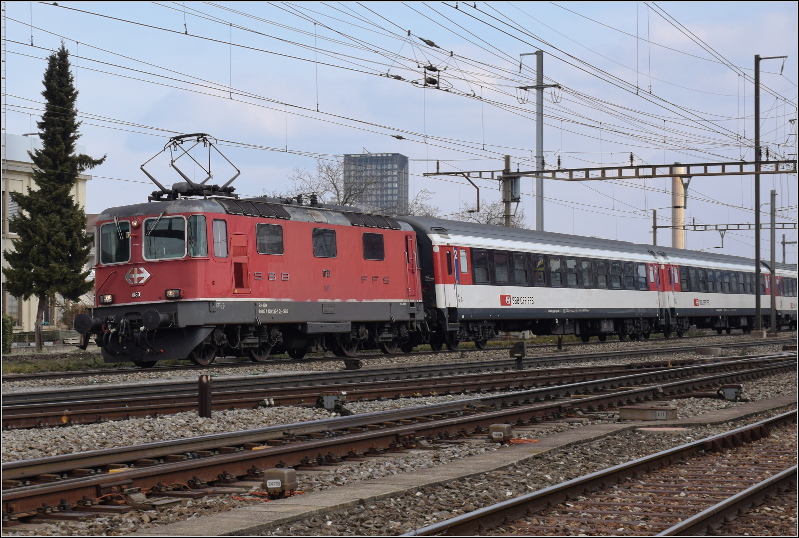 Re 4/4 II 11153 mit UIC X-Wagen in Pratteln. Februar 2024.