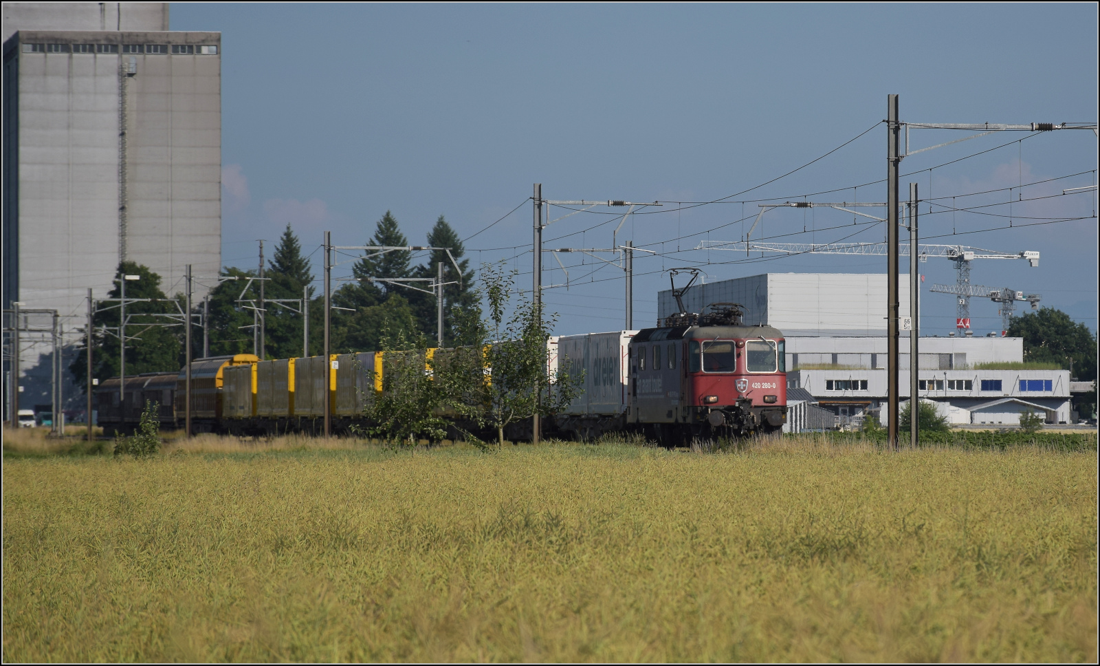 Re 4/4 II 11280 mit einem Postzug bei Hendschiken, Juni 2025.