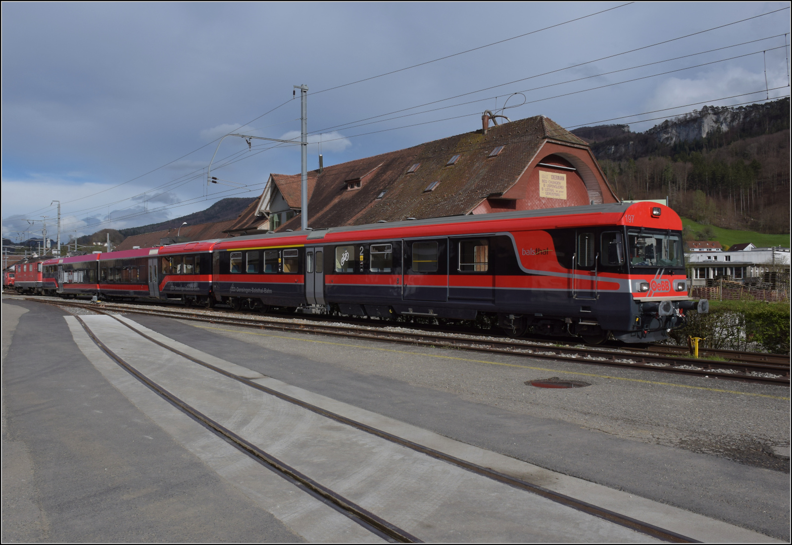 Re 4/4 III 11350 mit den beiden frisch renovierten Wagen der OeBB fährt in Balsthal ab. April 2024.