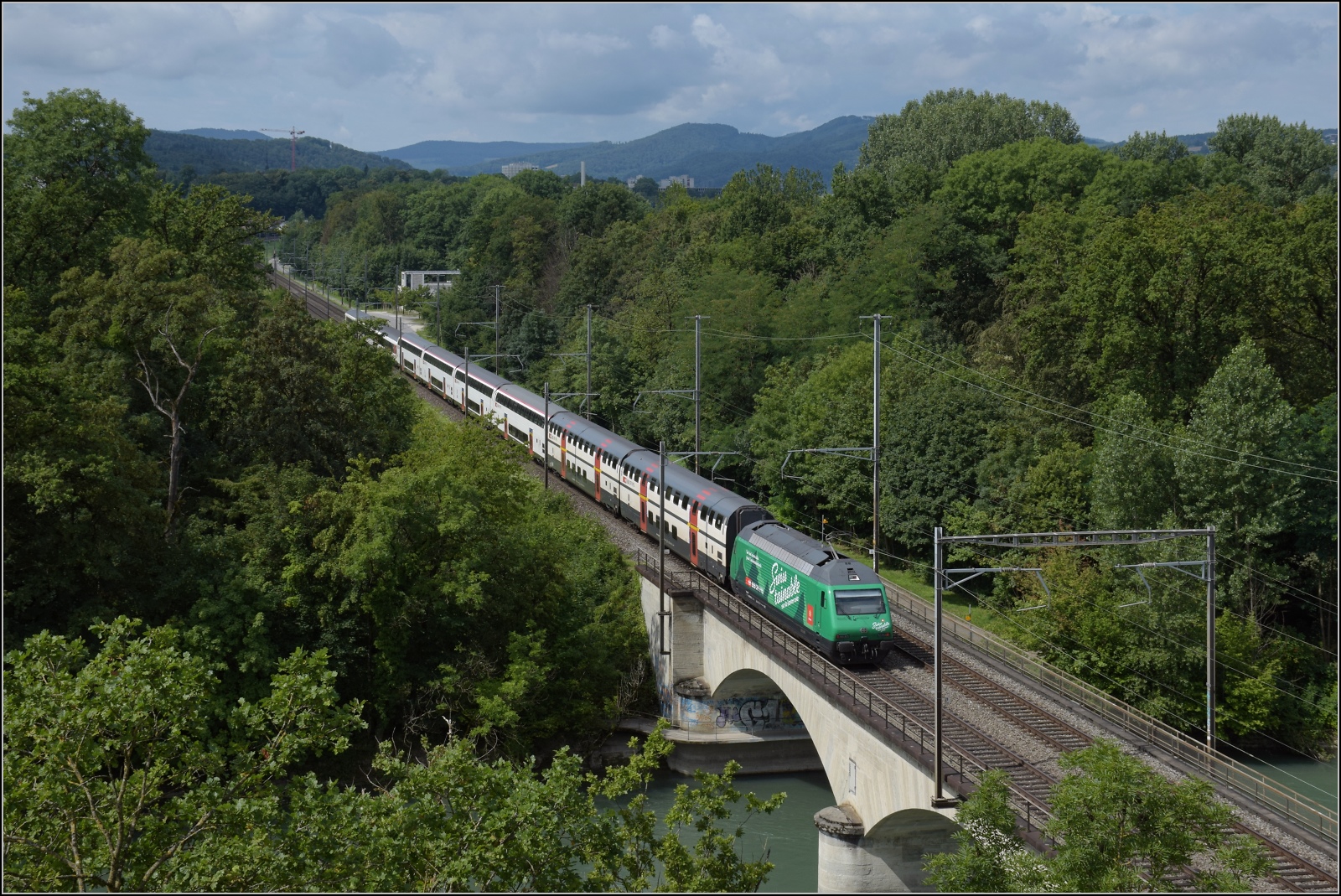 Re 460 010 mit Swisstainable-Werbung auf der Reussbrcke bei Vogelsang. Juli 2023.