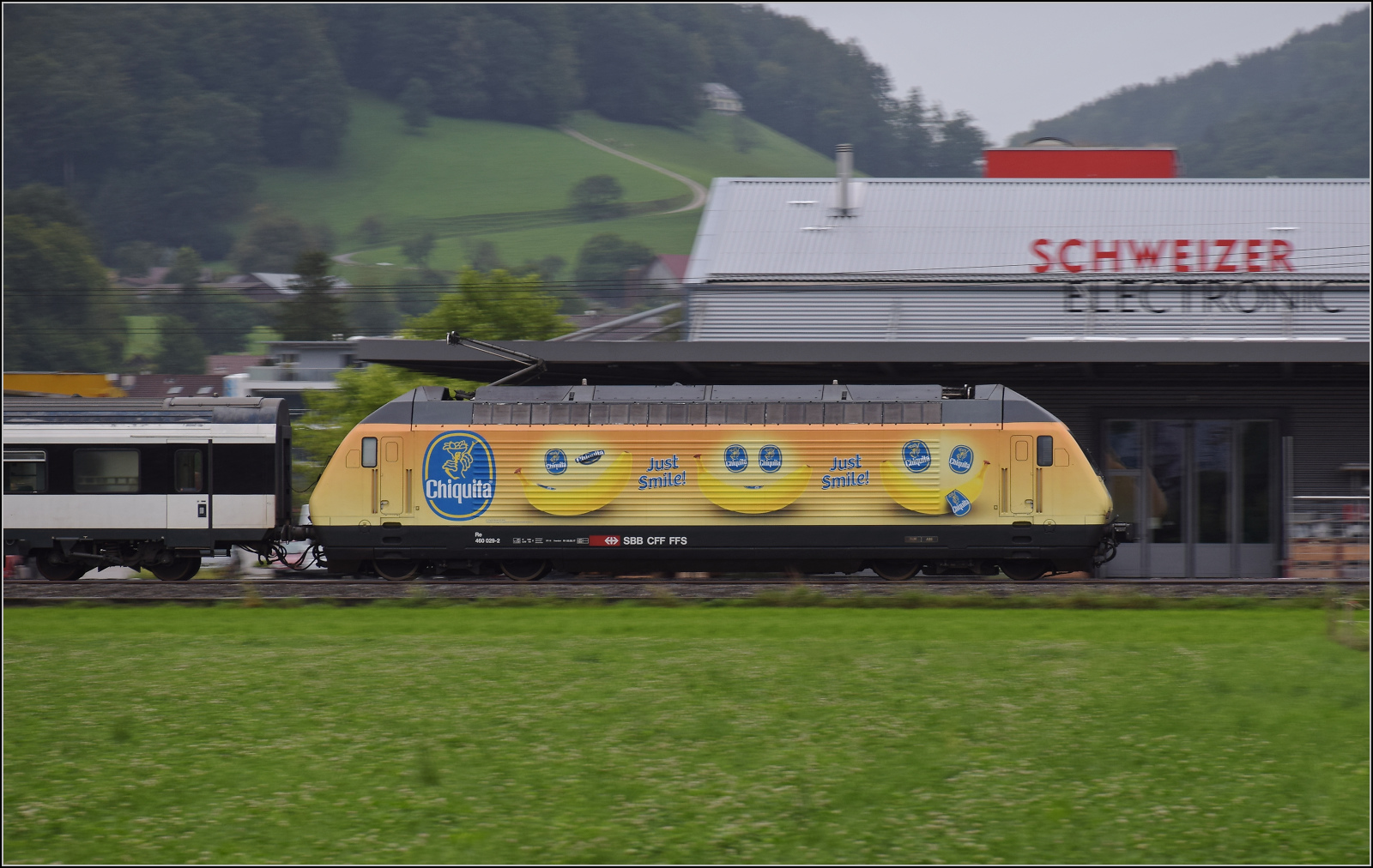 Re 460 029 mit Bananenwerbung zieht einen Fernzug mit EW IV-Wagen durch Reiden. August 2017.
