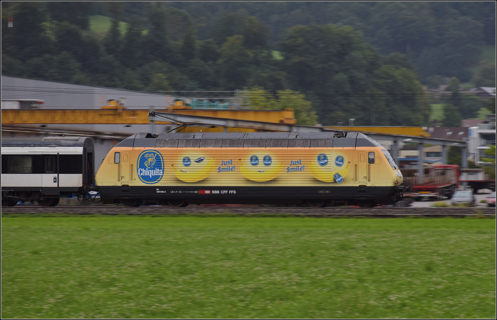Re 460 029 mit Bananenwerbung zieht einen Fernzug mit EW IV-Wagen durch Reiden. August 2017.