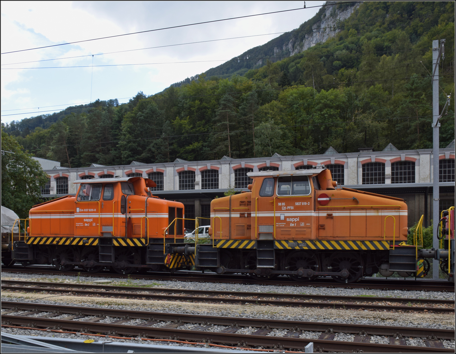 Sappi Em 2 mit Nummer Em 837 820 und Sappi Em 1, ausgeschrieben 98 85 5 837 819-2 CH-PFBi sind Henschel DH 500 und gerade ausquartiert in den Bahnhof Klus. Januar 2023.