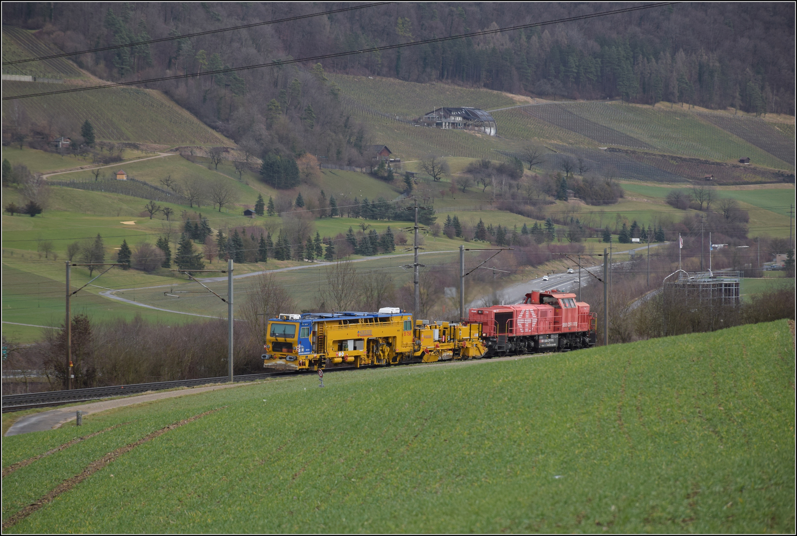 Schlechtwetter und ein Baustellendrama bei Frick. 

Am 843 020 der SBB Infrastruktur f�hrt mit einer Nivelier-Richt-Stopfmaschine B 758 von Scheuchzer (CH-SCHEU 40 85 9581 078) und dessen Anh�nger B 762 zum B�rsten des Schotterbetts in Richtung B�zberg. Februar 2026.