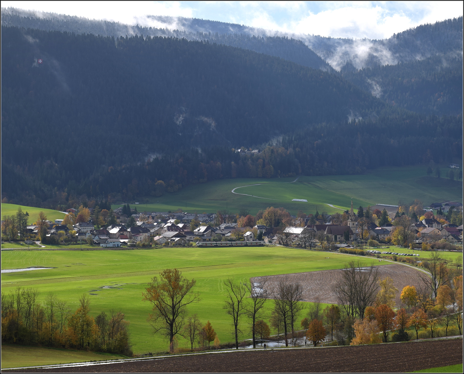 Überraschend fährt ein Flirt 3 von RER auf der Talstrecke im Val Travers durch. Môtiers, Oktober 2025.