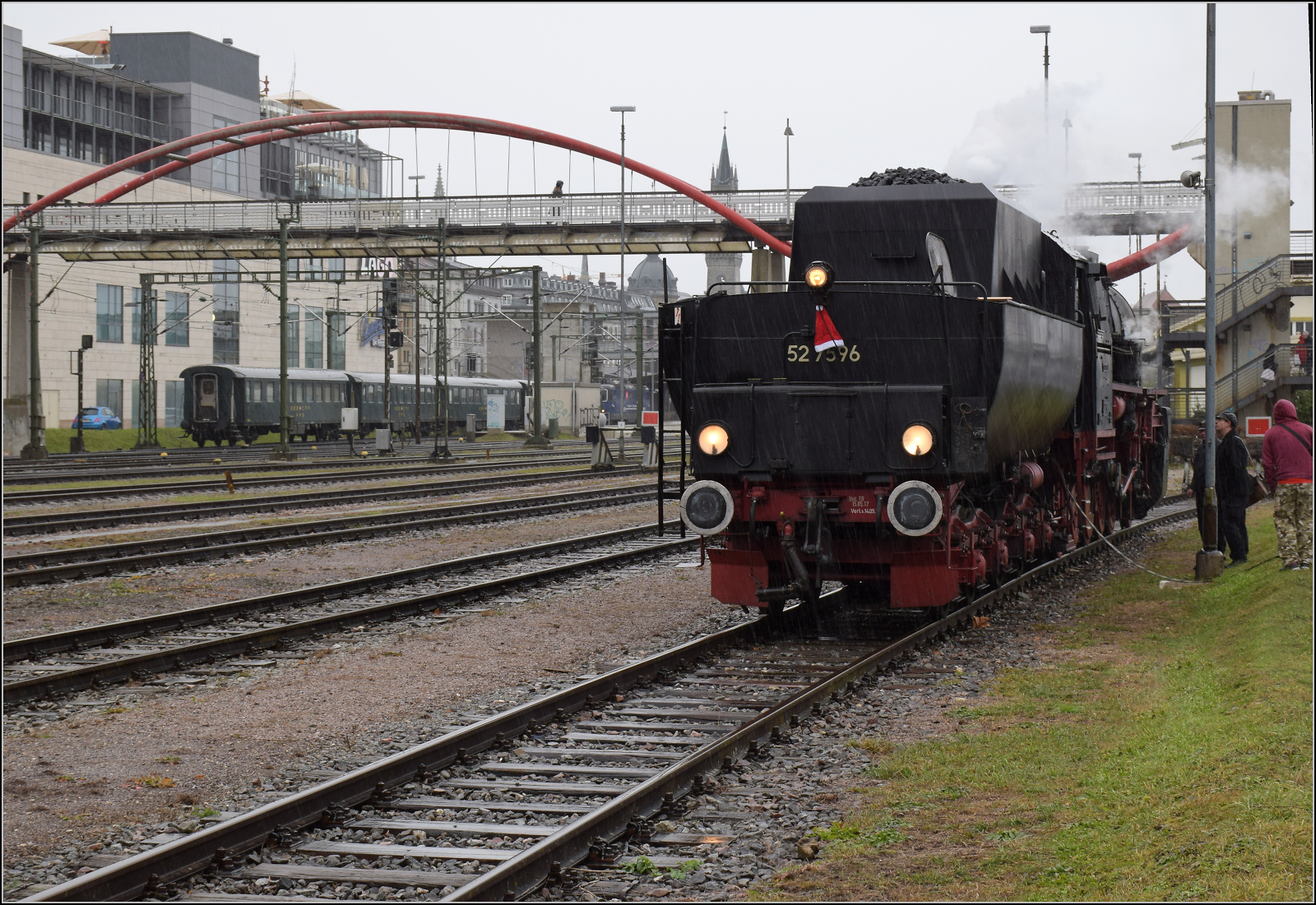 Weihnachtsmarktbesuch der EFZ.

52 7596 in strmendem Regen beim Auffllen der Wasservorrte auf dem ehemaligen Hafengleis im Bahnhof Konstanz. Unterdessen rangiert Re 421 379 ihren Wagenpark aus schweren Umbau-Stahlwagen auf Gleis 4.Dezember 2024.