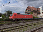 
185 302 mit einem Neuwagenpark in Weinheim. Juli 2023.