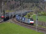 186 501 der Railpool begegnet Re 460 007 auf der Neubaustrecke hinter der Schallschutzmauer. Kaltenherberg, April 2023.