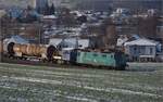 Re 430 115 von WRS mit Synopsis-Werbung schleppt die Rangierhilfe Tm III 9530 mit über den Bözberg.