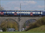 Der Doppelstockwagen mit Niederflureinsteig der S-Bahn Zürich mit Re 450 038 'Wollishofen' auf dem Eglisauer Rheinviadukt. April 2026.