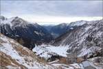 Blick über das Putschlav zu den Bergamasker Alpen. Unten in Cavaglia begegnen sich zwei Regionalzüge. Januar 2022.